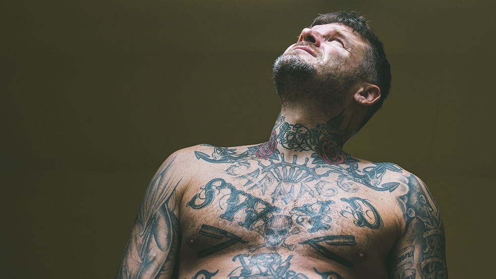HOKA fan Matthew Pritchard, topless and tattooed, looks up