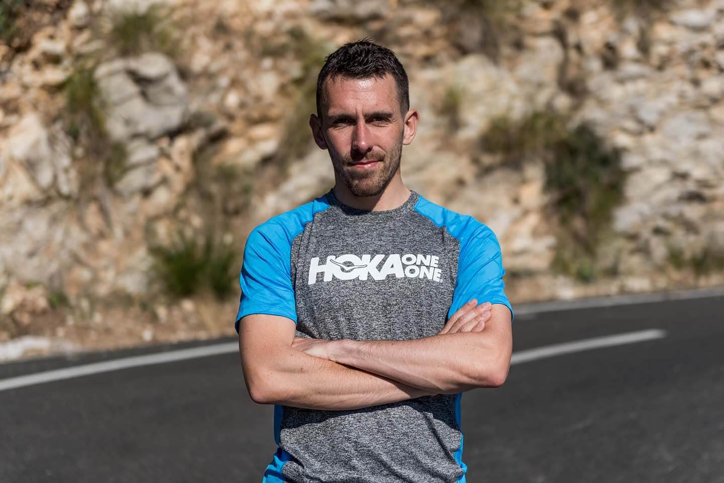 HOKA athlete Andrew Douglas stands with arms folded